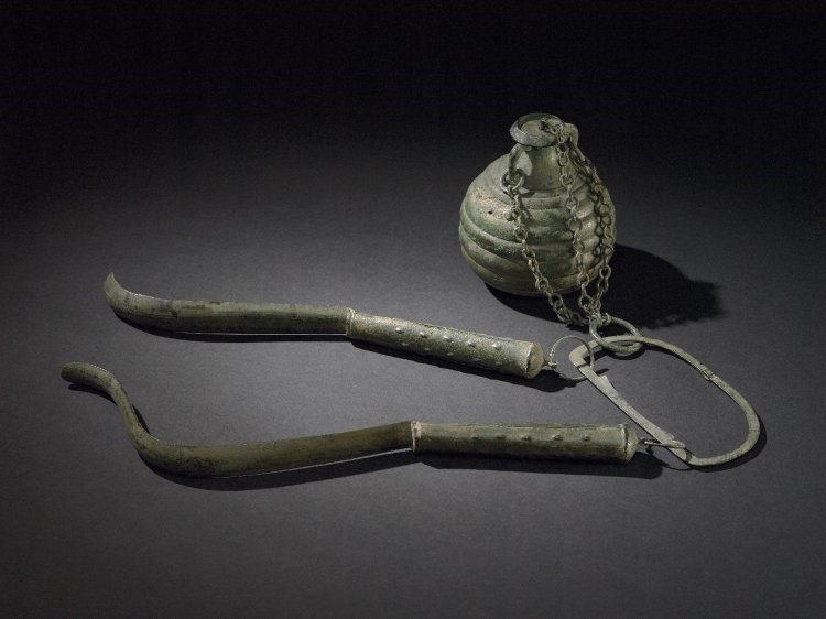Bronze athlete's toilet set consisting of an aryballos (oil-flask) and two strigils, linked by chains to a ring for hanging on the wall.