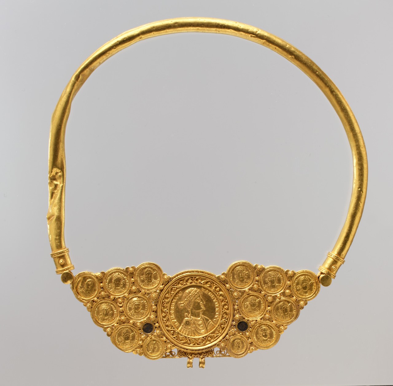 Pectoral with coins and pseudo-medallion, Byzantine, ca. 539–50. This pectoral necklace is composed of a plain, hollow neck ring attached to a frame set with a large central medallion flanked by coins and two small decorative disks. https://www.metmuseum.org/art/collection/search/464070