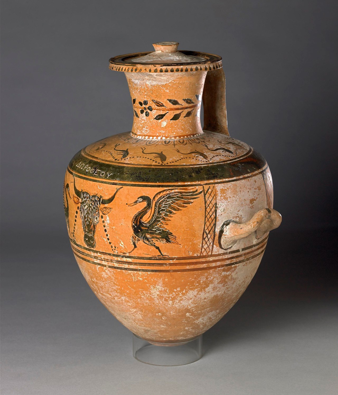 Hadra hydria decorated in the black-figure technique with a bucranium flanked by swans in a panel between the handles and dolphins on the shoulder. The Greek inscription Dorotheou, 'of Dorotheos', incised above the bull's head, is the name of the person whose ashes this vase originally contained. https://www.britishmuseum.org/collection/object/G_1995-1003-1