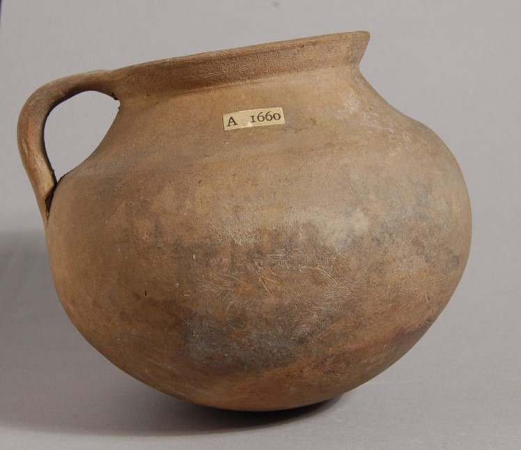 Unglazed pottery cooking-pot with a rounded body, a spreading rim and a strap handle from rim to shoulder.